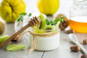 Homemade yogurt in a glass jar with honey, kiwi, nuts. photo