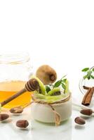 Homemade yogurt in a glass jar with honey, kiwi, nuts. photo