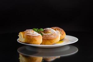 Baked goods. Sweet buns with cottage cheese filling and honey in a plate isolated on a black background photo