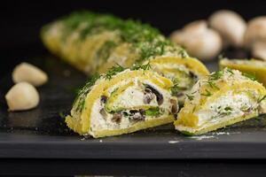 baked potato roll with cottage cheese filling with garlic and mushrooms, isolated on black background photo