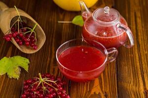 tea from ripe red viburnum on a wooden table . photo