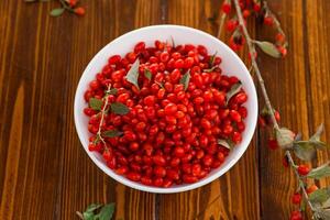 fresh ripe red goji berries in a bowl on a wooden table photo