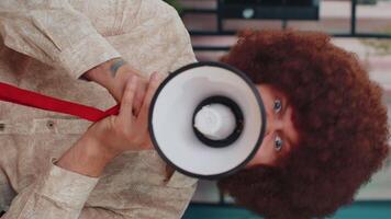 Young caucasian man talking with megaphone, proclaiming news, loudly announcing advertisement video
