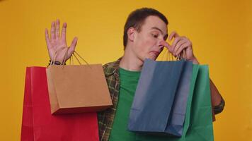 Happy tourist man showing shopping bags, advertising holidays discounts, amazed with low prices video