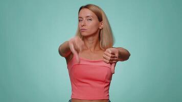 Upset woman in casual crop top showing thumbs down sign gesture, disapproval, dissatisfied dislike video