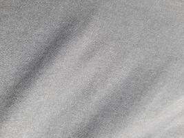 a close-up of a piece of gray fabric. The fabric appears to be woven, with a subtle texture visible in the weave. The color is a uniform, medium gray, with no discernible pattern or design. photo