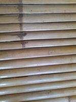 a horizontal arrangement of bamboo slats with a natural finish. The texture is rough and natural, emphasizing the raw characteristics of bamboo. photo