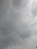 an overcast sky dominated by dense gray clouds, creating a moody and atmospheric scene. The soft light filtering through the clouds hints at possible rain or stormy weather. photo