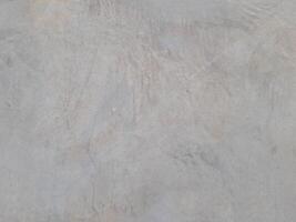 A plain gray textured surface with subtle irregular patterns and faint lines. The surface has a smooth yet natural appearance, resembling concrete or plaster with slight imperfections. photo