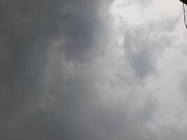 an overcast sky dominated by dense gray clouds, creating a moody and atmospheric scene. The soft light filtering through the clouds hints at possible rain or stormy weather. photo