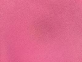 a close-up view of a smooth, pink-colored fabric. The texture is fine and uniform, creating a soft and elegant appearance with no visible patterns or folds photo