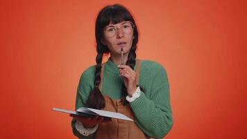 Thoughtful journalist woman making notes, writing down thoughts with pen into notepad notebook diary video