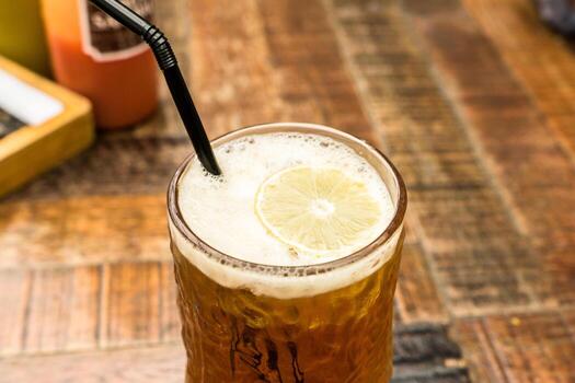 A refreshing lemon tea served in a glass on a beautiful wooden table at a restaurant. Cutlery is visible in the background, enhancing the dining atmosphere photo