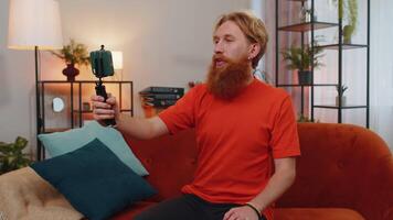 Bearded man blogge taking selfie on smartphone communicating call home online with subscribers video