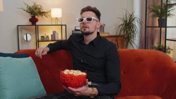 Guy sitting on couch eating popcorn and watching interesting TV serial, sport game online at home video