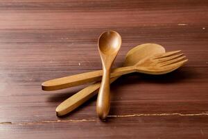 An isolated wooden spoon and fork placed on a wooden background, showcasing their natural texture and design. The simplicity of the scene highlights the rustic elegance photo