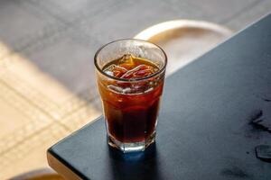An iced americano served on a table at a coffee shop, with a cozy cafe ambience in the background. The cool beverage adds to the relaxed atmosphere of the cafe setting photo