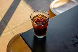 An iced americano served on a table at a coffee shop, with a cozy cafe ambience in the background. The cool beverage adds to the relaxed atmosphere of the cafe setting photo