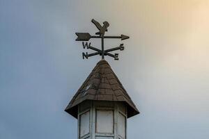A wind vane on display with a stunning sky backdrop and rays of sunlight shining through. This image captures the beauty of the weather vane in a serene outdoor setting photo