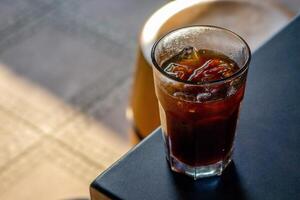 An iced americano served on a table at a coffee shop, with a cozy cafe ambience in the background. The cool beverage adds to the relaxed atmosphere of the cafe setting photo