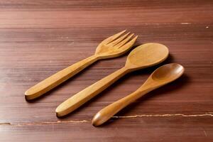 An isolated wooden spoon and fork placed on a wooden background, showcasing their natural texture and design. The simplicity of the scene highlights the rustic elegance photo