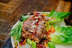 A flatlay shot of a beef salad topped with nuts and dressing, placed on a wooden table. The image also includes space for text, ideal for a customizable layout photo
