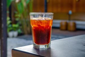 An iced americano served on a table at a coffee shop, with a cozy cafe ambience in the background. The cool beverage adds to the relaxed atmosphere of the cafe setting photo