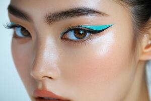 Contemporary Makeup Artistry with Vibrant Aqua Graphic Liner on Fresh Faced Asian Model photo