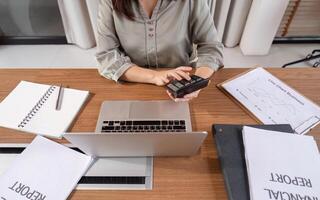 Professional Accountant Analyzing Financial Documents with Laptop and Calculator in Modern Office Setting for Business and Finance Solutions photo
