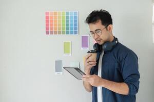 Creative Graphic Designer Planning a New Project with Color Swatches and Headphones in Modern Office Setting photo