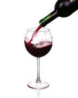 Red wine pouring on white background photo