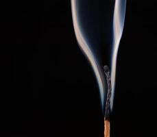 Burned match with clouds of smoke on a black background photo