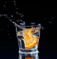 Slice of lemon splashing into a glass of water photo