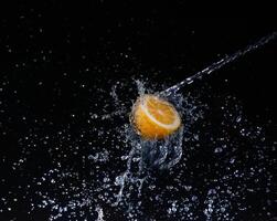 A high-speed shot of a lemon with splashing water, on a black background. photo