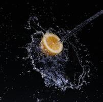 A high-speed shot of a lemon with splashing water, on a black background. photo