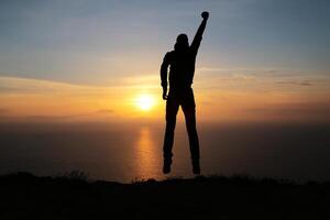 Silhouette of running man against the colorful sky. Silhouette of running man on sunset fiery background photo