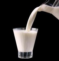 Splash in a glass with milk isolated on black photo