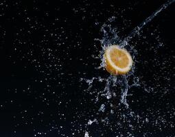 A high-speed shot of a lemon with splashing water, on a black background. photo