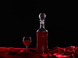 glass and bottle of wine on a dark background silk photo