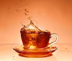 Cup of tea on glass with orange background photo
