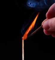 Ignition of a match, with smoke on dark background photo