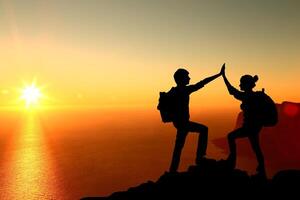 The Silhouette of two man with success gesture standing on the top of mountain photo