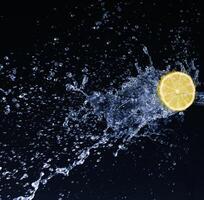 Half a lime falling into the water isolated on a black background photo