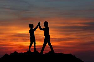 The Silhouette of two man with success gesture standing on the top of mountain photo