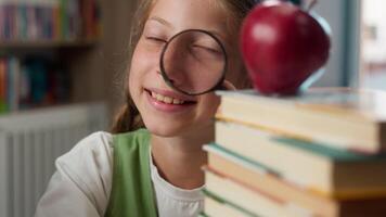 Happy smiling playful Caucasian school child kid teenage learner student pupil schoolgirl looking through magnifying glass play studying learning search books apple inside education classroom library video