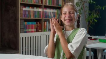 Happy playful glad Caucasian smiling little girl child schoolgirl kid student learner schoolkid looking at camera clapping hands celebrate clap applaud funny applauding inside classroom school lesson video