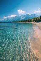 A tranquil beach with clear water and mountains in the background on a sunny day photo