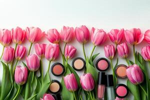 Colorful makeup products arranged with fresh pink tulips on a white background in soft light photo