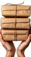 Hands holding stacked wrapped packages tied with twine against a plain background photo