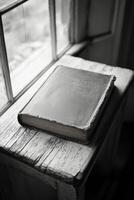A weathered book resting on a rustic table near a window, capturing timeless beauty and history photo